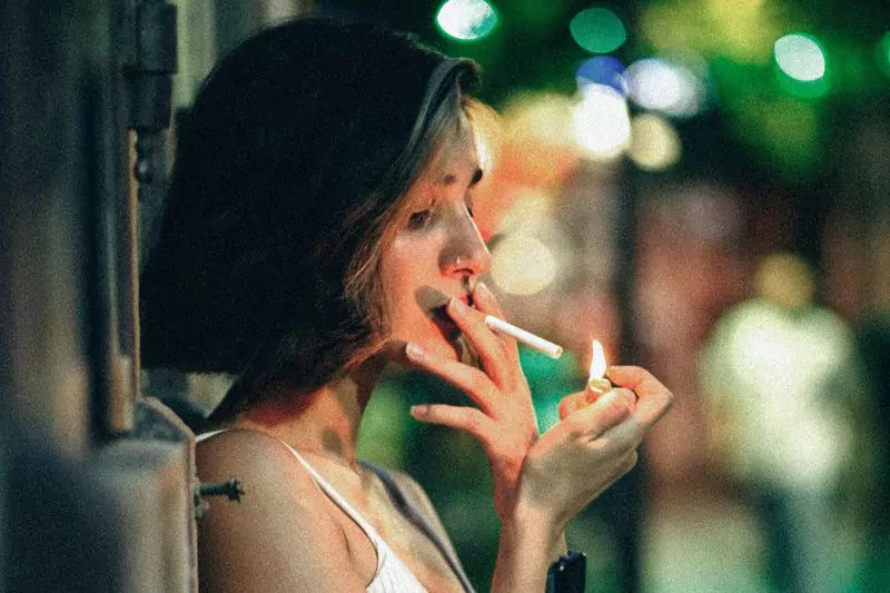 Young woman lighting a cigarette on the street in Bangkok, before switching to nicotine pouches.